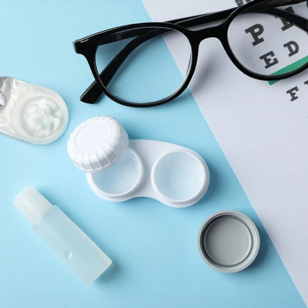 Eyeglasses, contacts, and maintenance tools lying atop an eye chart